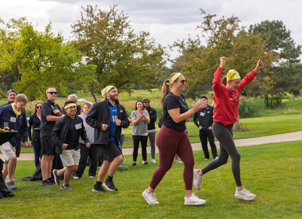 A diverse corporate team participating in a high-energy outdoor relay challenge, team building, team building chicago summer, outdoor team engagement, group corporate activities for summer in chicago